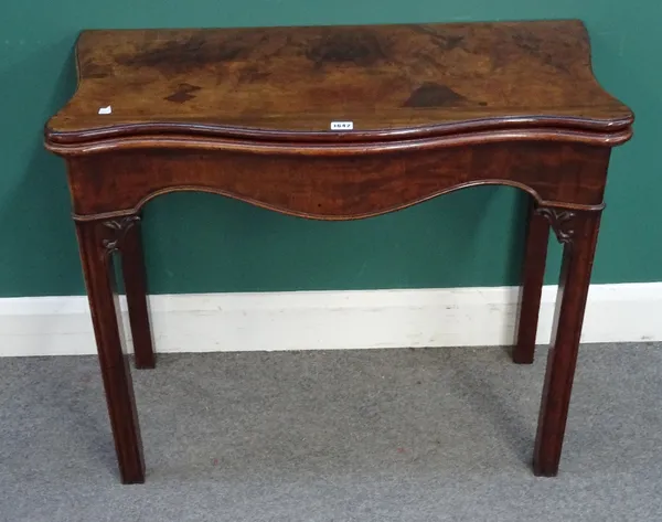 A mid-18th century mahogany concertina action card table, the serpentine top on channelled square supports, 89cm wide x 74cm high x 45cm deep. 1