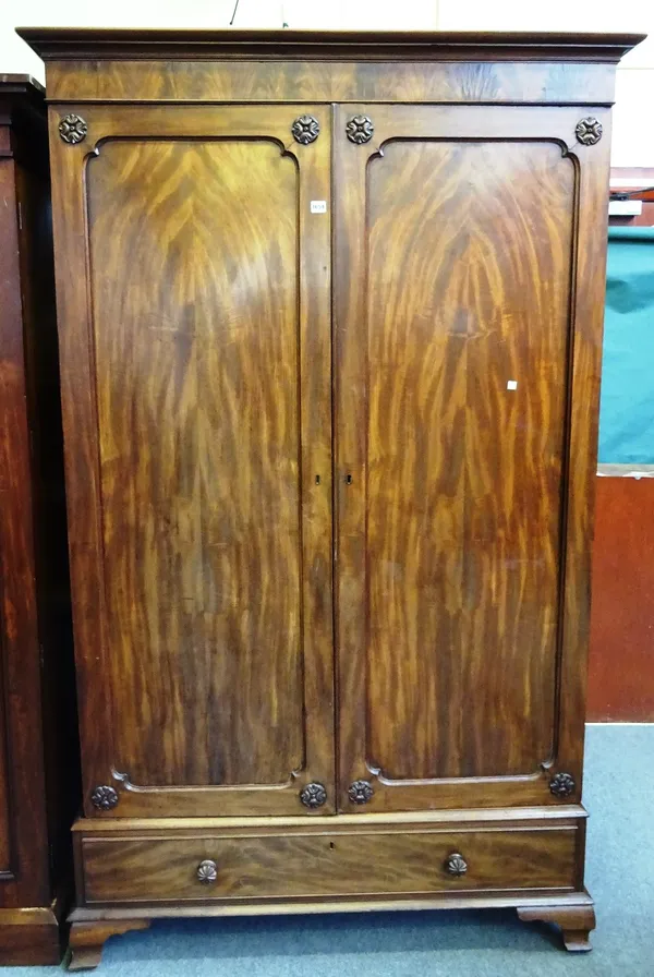 A George IV mahogany wardrobe, the pair of shaped panel doors over one long drawer, on ogee bracket feet, 130cm wide x 214cm high x 61cm deep.