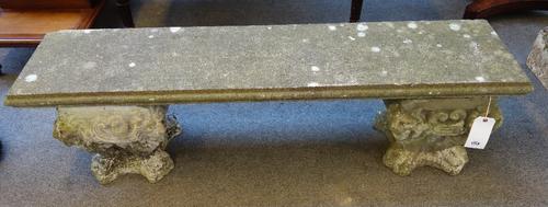 A pair of reconstituted stone garden benches, each with a rectangular slab top on shaped square bases with lion face masks, 153cm wide x 36cm deep x 4