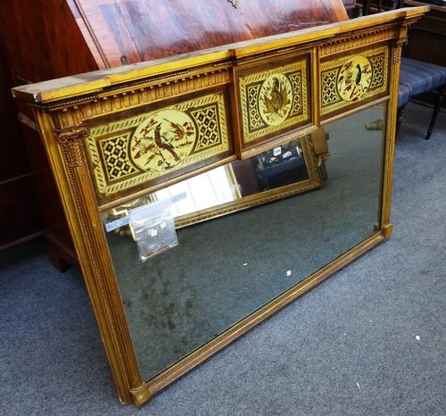 A Regency style gilt framed wall mirror, with painted triple panel top and rectangular mirror plate, flanked by reeded columns, 154cm wide x 93cm high