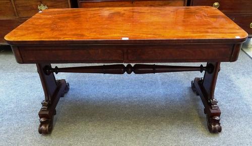 A William IV mahogany centre library table, the rounded rectangular top with pair of frieze drawers, on carved trestle end standards and four scroll f
