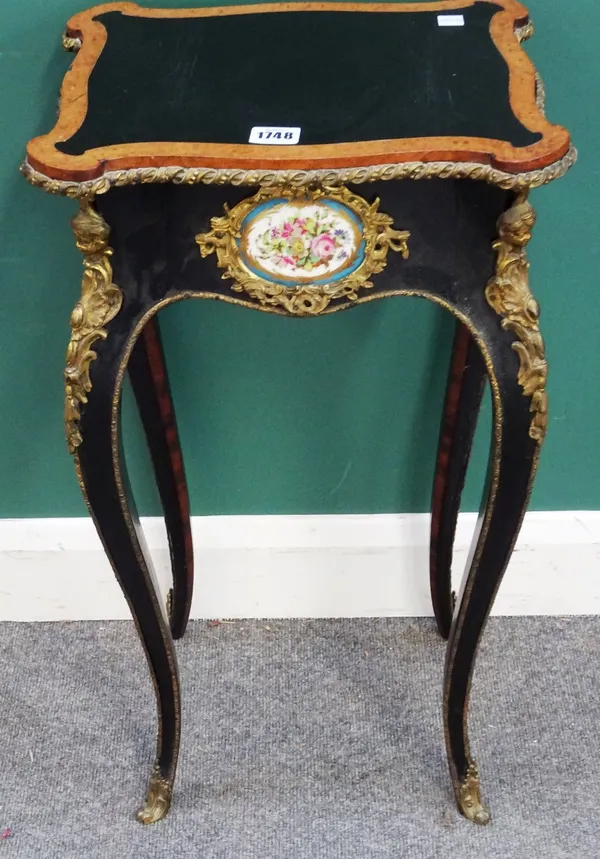 A 19th century French gilt metal mounted ebonised and amboyna banded jardiniere stand, of serpentine outline, with ceramic mounted frieze on four scro