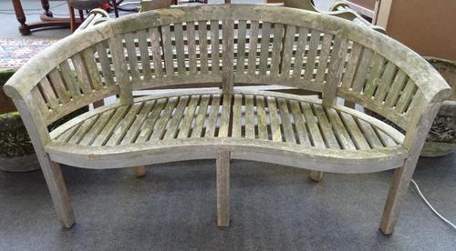 A 20th century hardwood tub back garden bench, with serpentine seat on block supports, 87cm high.