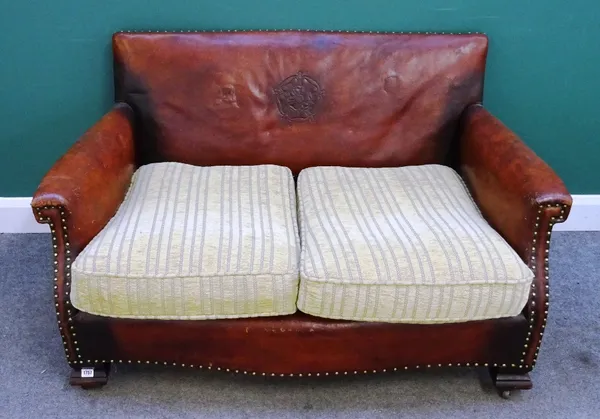 A mid-20th century studded brown leather upholstered two seat sofa with embossed Tudor rose back, 130cm wide x 75cm deep x 77cm high, together with a