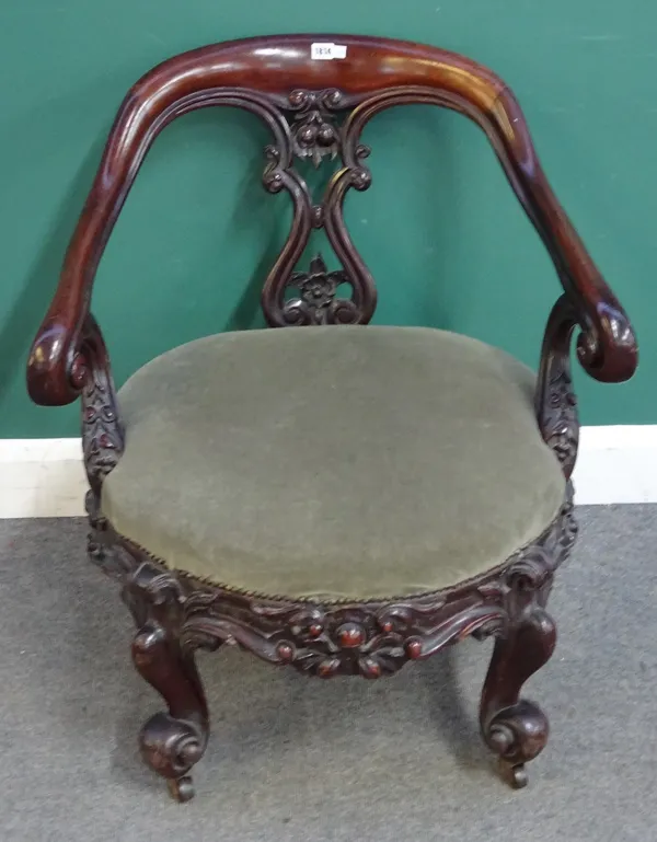 A Victorian mahogany framed open armchair, with deep floral carved frieze, on four scroll supports, 77cm wide x 83cm high.