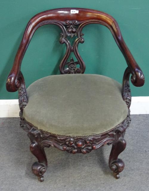 A Victorian mahogany framed open armchair, with deep floral carved frieze, on four scroll supports, 77cm wide x 83cm high.