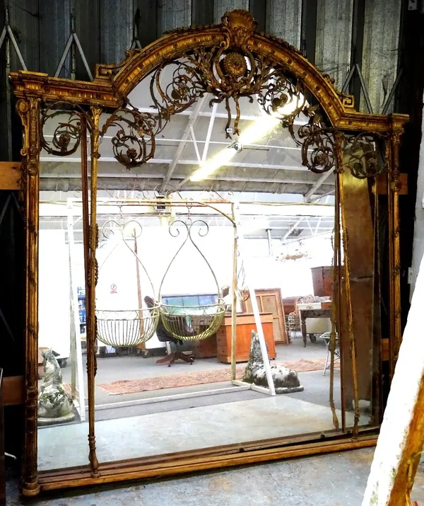 A massive 19th century gilt framed wall mirror, the arch top with ribbon tied cartouches surrounded by floral sprays, 245cm wide x 245cm high.