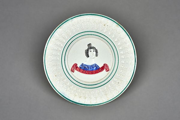 A commemorative Queen Victoria pottery plate, 19th century, possibly Scottish, moulded with a head and shoulders portrait above a titled banner, flowe