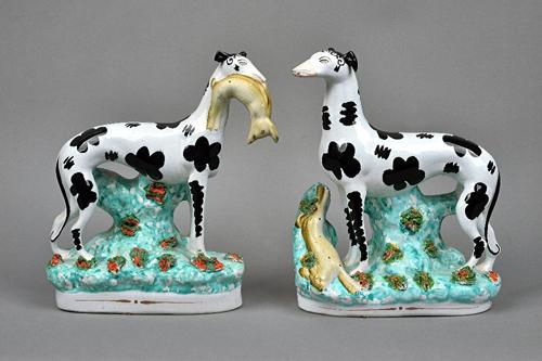 A pair of Staffordshire pottery models of `Disraeli greyhounds', mid 19th century, each painted with black patches, modelled standing, one with a hare