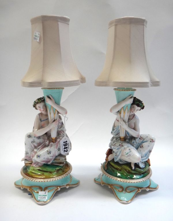 A pair of Continental porcelain candlesticks, French or German, late 19th, each modelled as a kneeling classical young woman holding a tall vase, fiit