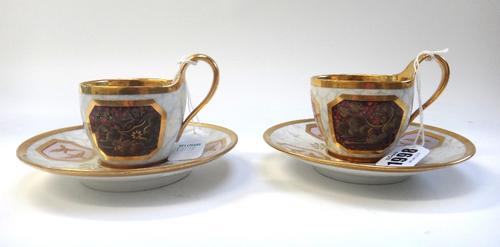 Two Berlin porcelain cabinet cups and saucers, 19th century each internally gilt with matching gilt handles, the exterior with varying gilt silhouette