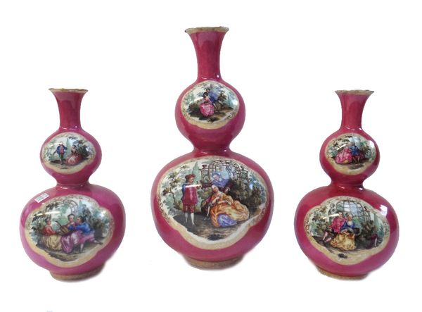 A garniture of three Dresden pink ground porcelain vases, 20th century each of double gourd form detailed with courting couples within gilt foliate ca