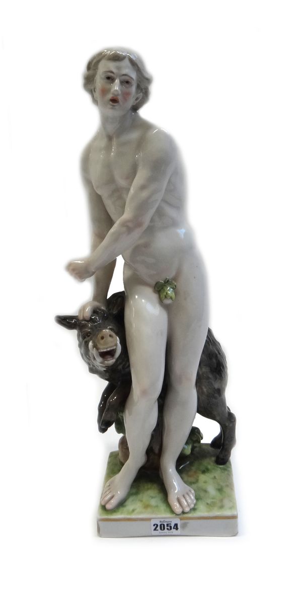 An early 20th century Continental porcelain figure group, modelled as a young naked man holding a boar atop a tree trunk and naturalistic base, blue p