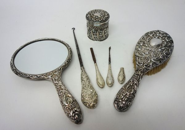 A silver lidded frame to hold a glass toilet jar, with floral, foliate and scroll embossed decoration, Chester 1901 and silver mounted dressing table