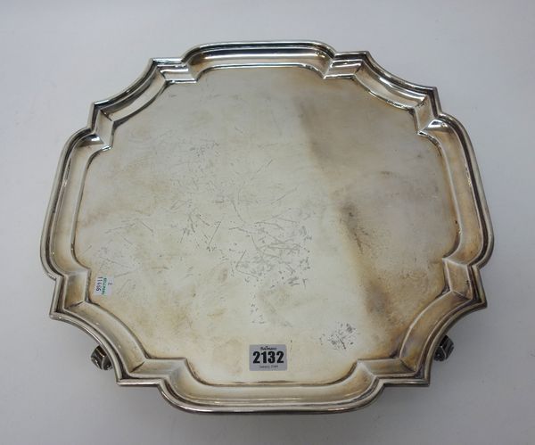 A silver salver, of shaped square form, with a pie-crust rim, in the Chippendale style, raised on four scrolling feet, in the early 18th century taste