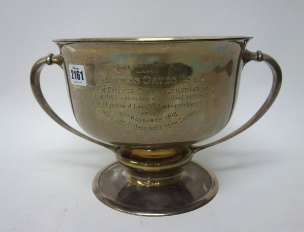 A silver twin handled large trophy bowl, presentation inscribed 'To Thomas Oates Esq by the Butcher's Charitable Institution', raised on a circular fo