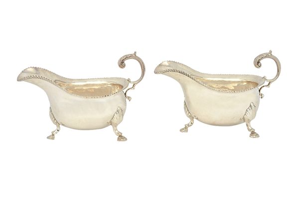 A pair of silver sauceboats, each with a scrolling handle, gadrooned rim and raised on three hoof shaped feet, Birmingham 1979, combined weight 550 gm