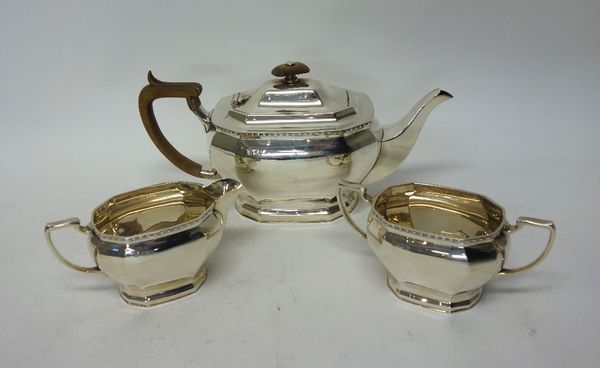 A silver three piece tea set, comprising; a teapot, a twin handled sugar bowl and a milk jug, each piece of bombe form, with decorated rims, the teapo