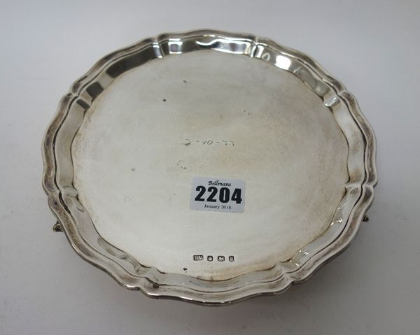 A silver salver, of shaped circular form, with a pie-crust rim, in the Chippendale style, raised on three feet, diameter 20cm, Sheffield 1932, weight