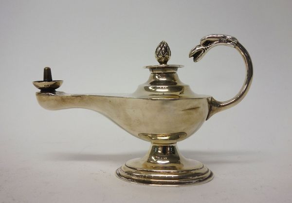 A silver table lighter, formed as a classical oil lamp, the terminal of the handle modelled as a bird's head, Birmingham 1935, weight 119 gms.