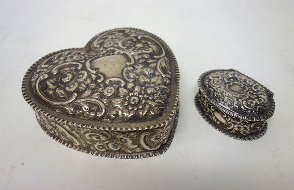 A Victorian silver hinge lidded box, of heart shaped form, with floral, foliate and scroll embossed decoration, gilt within, Birmingham 1893 and a Vic