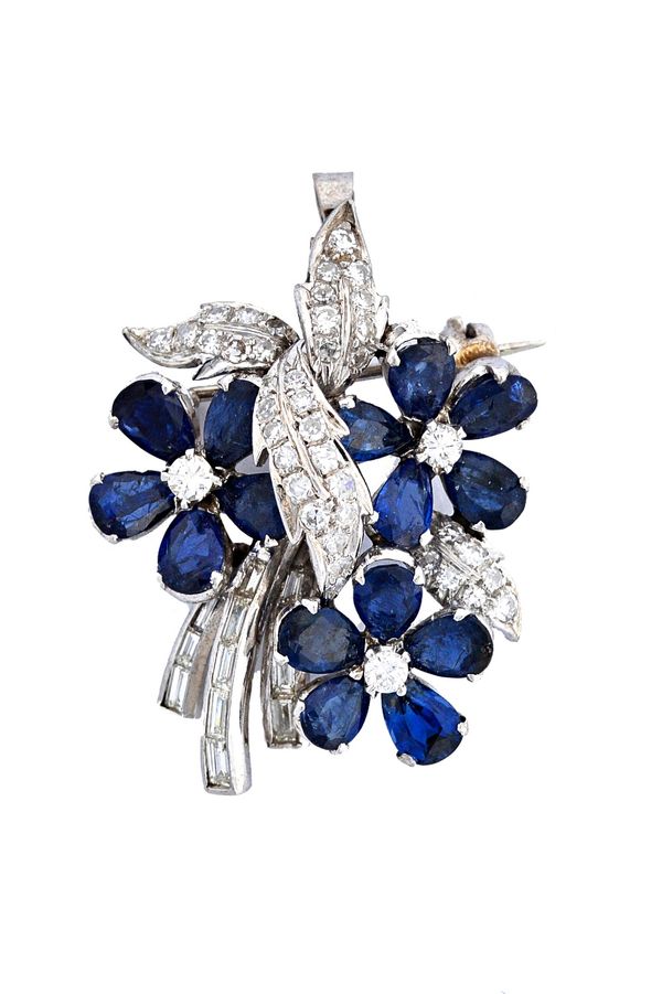 A sapphire and diamond set pendant brooch, designed as a floral and foliate spray, the three flowerheads mounted with a central circular cut diamond,