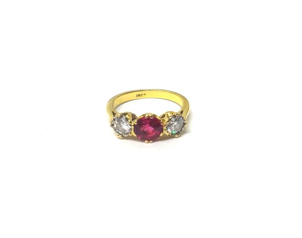 A gold, synthetic ruby and diamond set three stone ring, claw set with the circular cut synthetic ruby at the centre, between two circular cut diamond