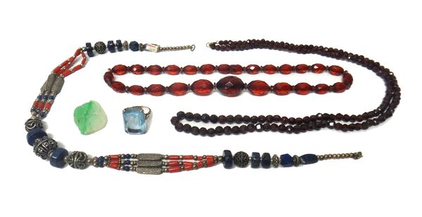 A single row necklace of graduated faceted garnet beads, two further bead necklaces, a small carved jade panel and a pale blue gem set dress ring, det