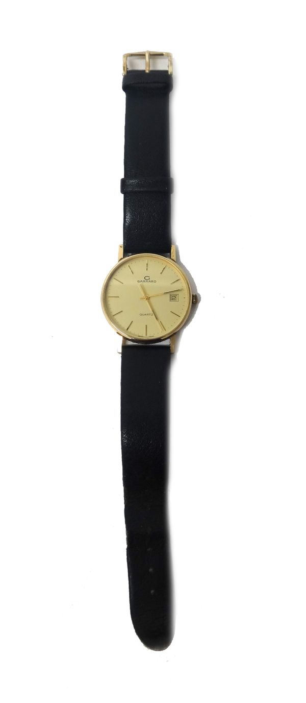 A Garrard Quartz 9ct gold circular cased gentleman's wristwatch, the signed gilt dial with gilt baton numerals, centre seconds and with a date of the