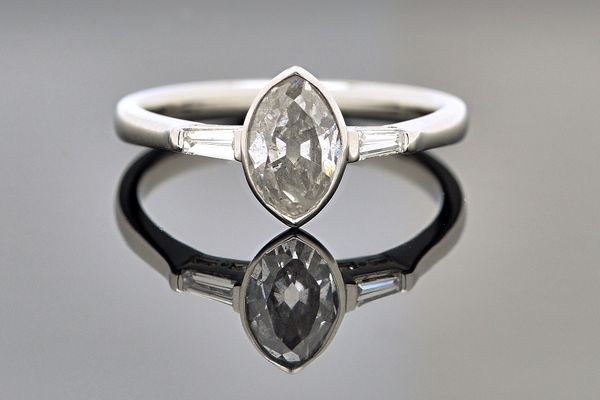 A platinum and diamond ring, mounted with the principal marquise shaped diamond at the centre, between tapered baguette diamond set single stone shoul