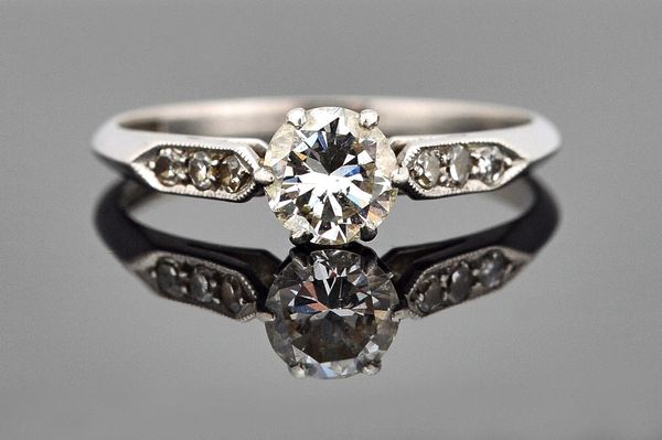 A platinum and diamond ring, claw set with the principal circular cut diamond at the centre, between diamond set three stone shoulders, ring size N an