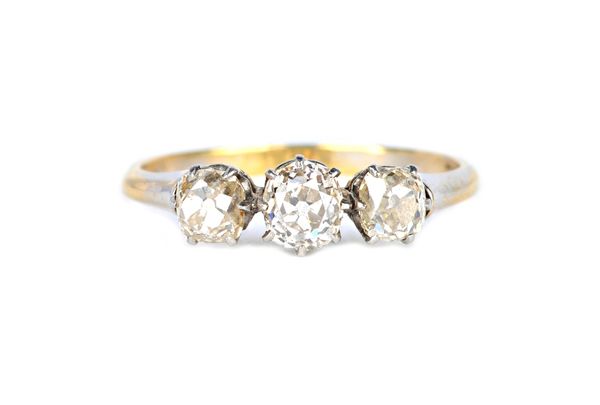 A gold and diamond three stone ring, claw set with a row of cushion shaped diamonds and with the principal diamond mounted at the centre, detailed 18