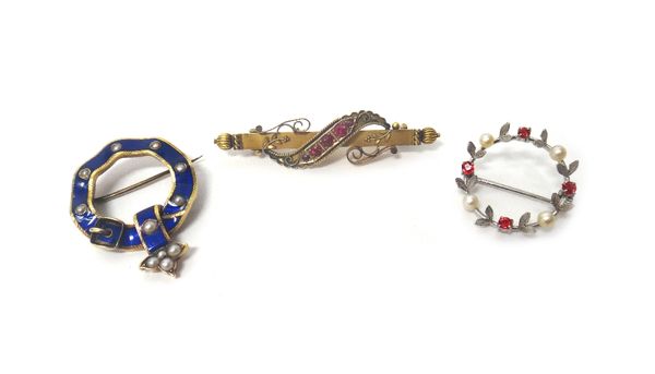 A gold, blue enamelled and half pearl set brooch, in a buckle and strap design, a late Victorian 15ct gold and red gem set bar brooch, with scrolled m