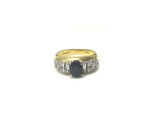 An 18ct gold, sapphire and diamond ring, claw set with the oval cut sapphire at the centre, between diamond set sides, mounted with circular cut and b