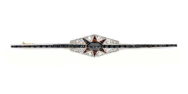 A diamond and black onyx Art Deco bar brooch, mounted with the principal oval black onyx to the centre, in a star shaped black onyx surround, in a geo