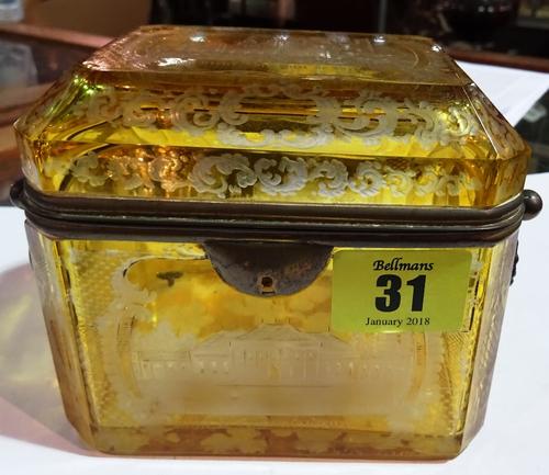 A Bohemian amber glass casket, late 19th century, engraved all over with architectural scenes against a canted rectangular body and brass mounts (a.f)
