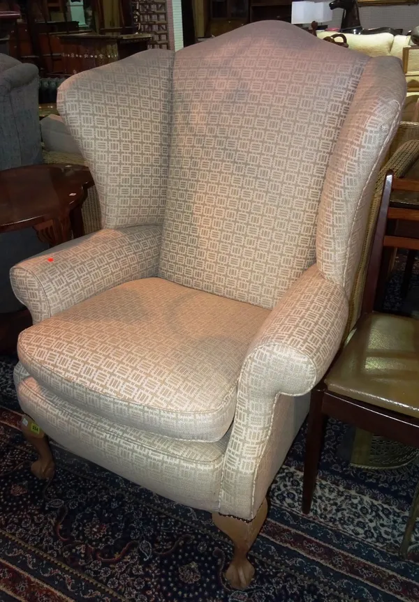 A 20th century upholstered wingback armchair, on ball and claw feet.  G5