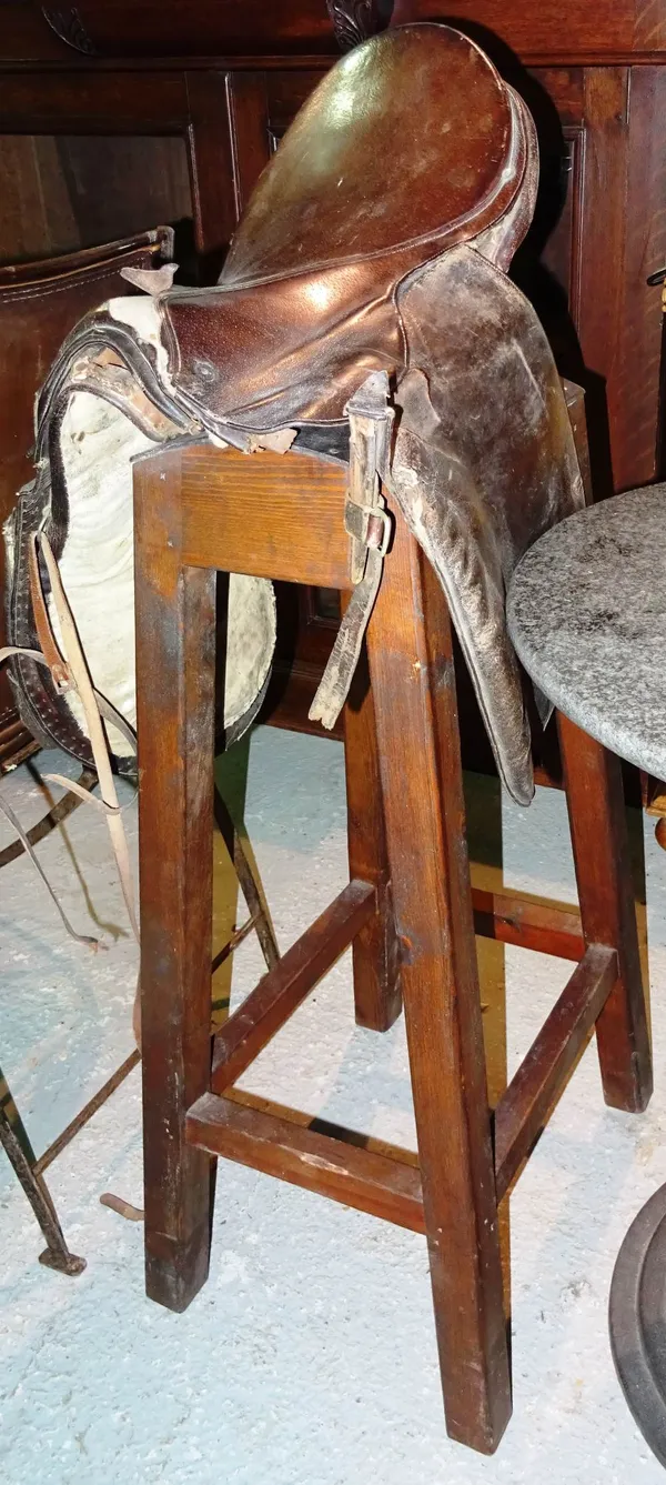 A pair of 20th century stained pine saddle stands, together with a brown leather horse saddle, (3).   B6