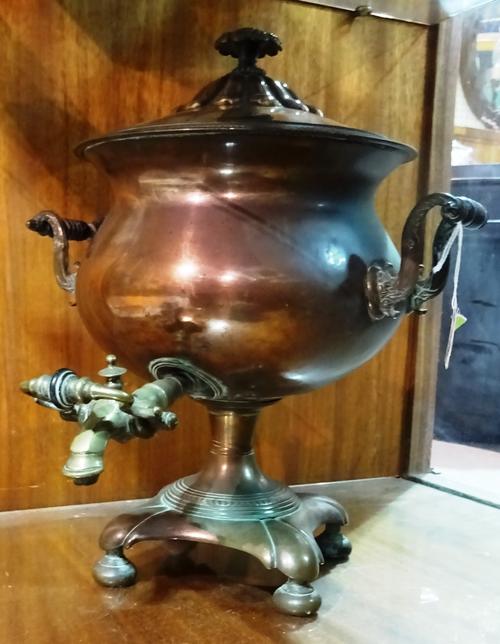 A copper and brass mounted samovar, early 19th century, of circular form, with twin handles, brass spout, a square shaped base and four bun feet.   CA