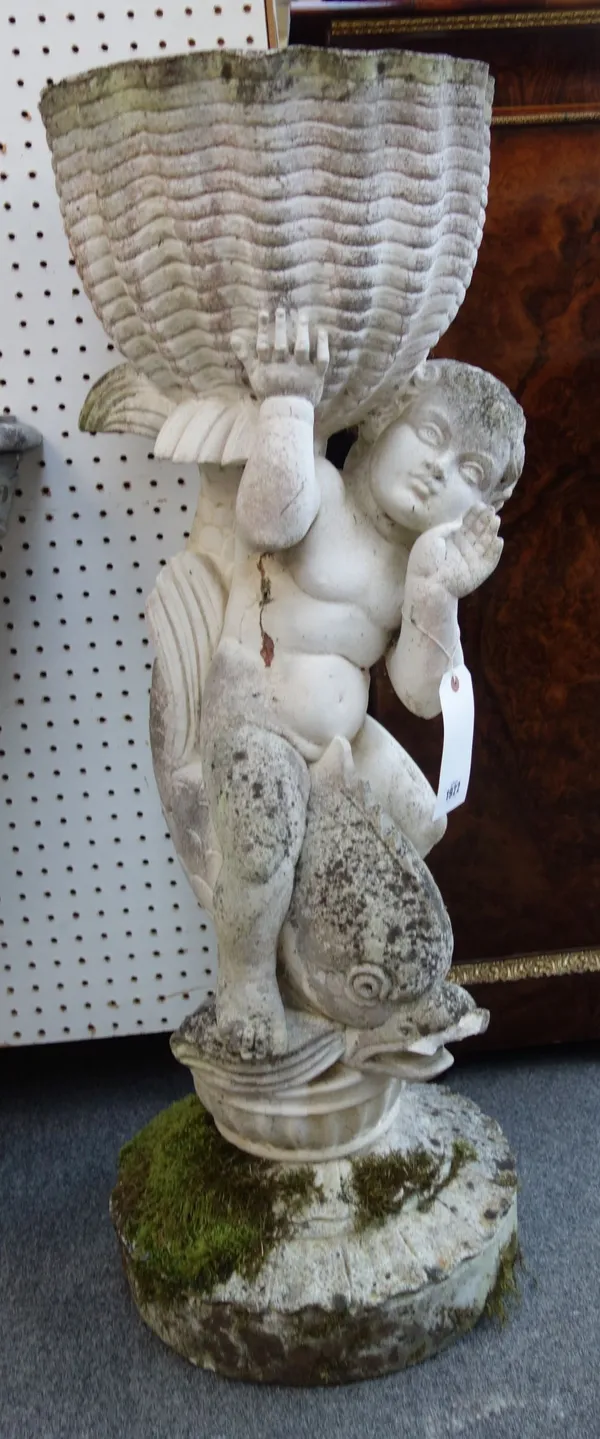 A pair of reconstituted stone figures of cherubs riding dolphins, holding scallop shaped bowls, 35cm wide x 100cm high, (2).  OUT