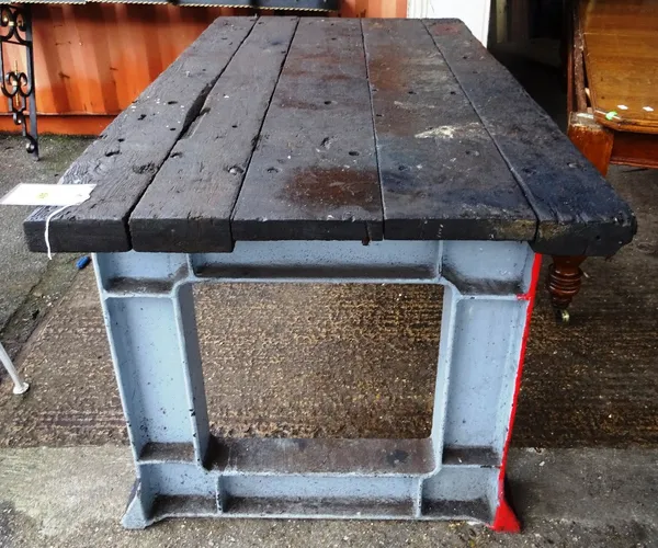 An early 20th century work bench on heavy cast iron base, with plank top, 162cm wide x 89cm high.    OUT