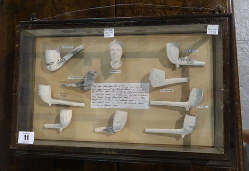 A collection of clay pipe bowls, 16th century style and later examples, 20th century, displayed in four glazed wooden cases, each titled with central