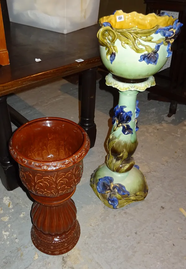 An early 20th century green and blue glaze floral moulded jardiniere and stand and a brown glaze jardiniere and stand, (4).  K2