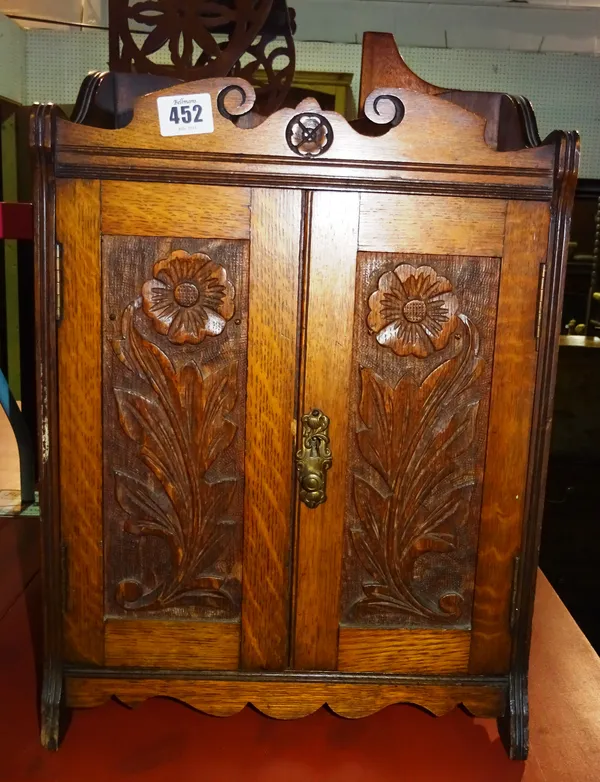 An early 20th century oak hanging smoker's cabinet, with floral carved panel doors, 32cm wide x 43cm high.  I8