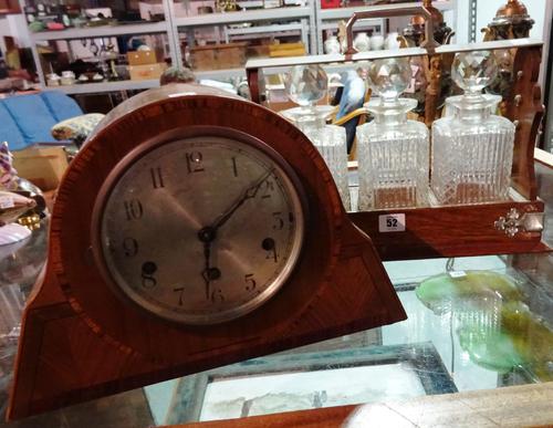 An early 20th century mahogany mantel clock, 22cm high and an oak bound tantalus with decanters, (2).  CAB