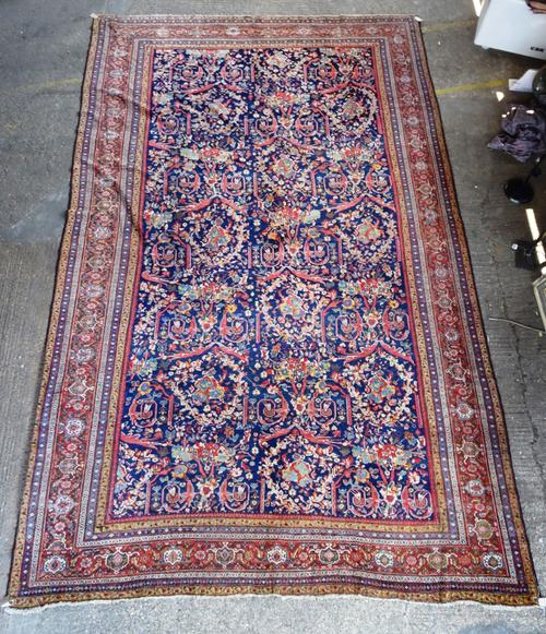 A late 19th century Fereghan carpet, dark blue field with repeating polychrome floral spray and shield decoration, deep red main border, (reduced + re