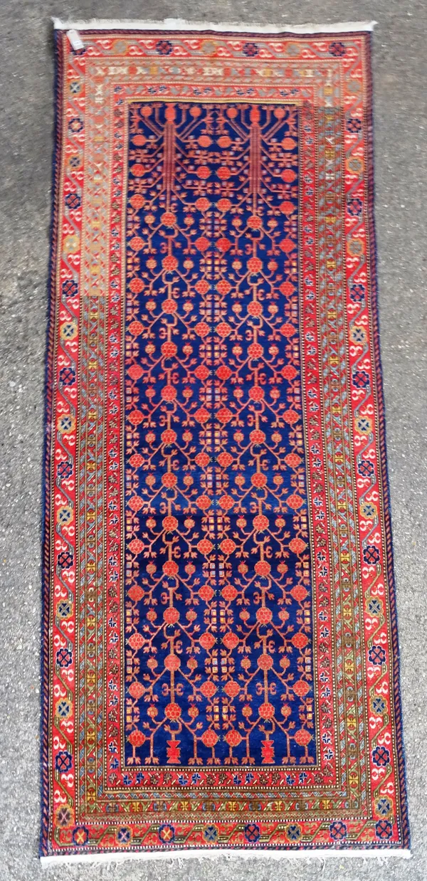 A Khotan carpet, the indigo field with an allover plant design bearing madder round flowerheads; a main madder rosette and vine border, 407cm x 166cm