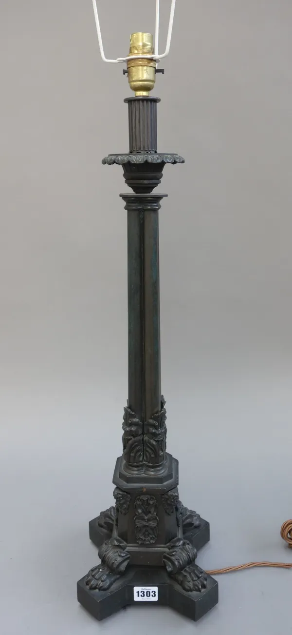 A Victorian style patinated bronze table lamp, cast with four conjoined pillars, over a canted square base and four lion paw feet, with a pleated silk