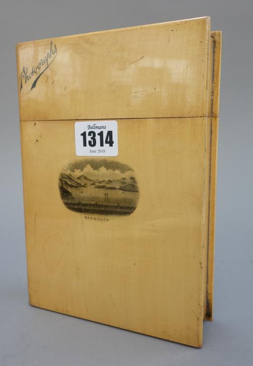 A Mauchline ware photograph album shaped as a book, printed with a coastal scene from 'Barmouth', 19cm high, a pair of mahogany bookends carved as mar