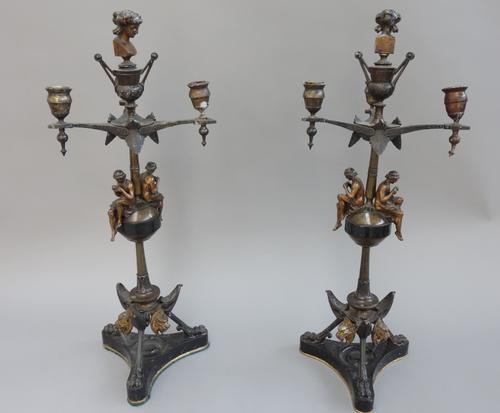A pair of patinated bronze three branch candelabra, late 19th century, each with female bust finial and opposing piccolo players to the knopped stem,